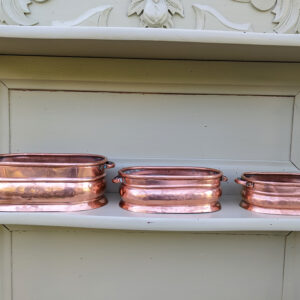 Three vintage copper planters displayed on a shelf