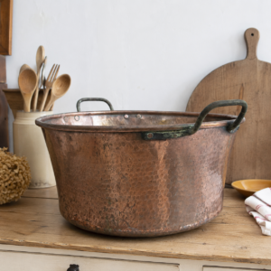 Large antique hammered copper cauldron with iron handles and rich aged patina displayed from above