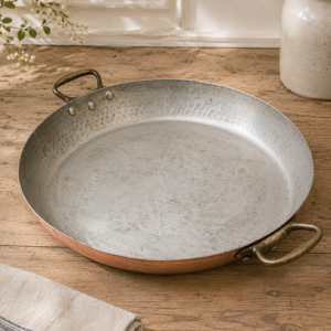Large vintage copper paella pan with hammered finish and riveted bronze handles in French style