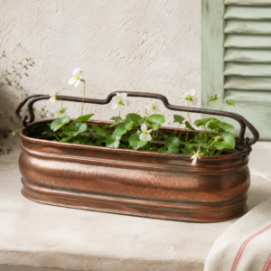 Vintage French copper planter with rolled edges and wrought iron handles in an elongated oval shape for French country decor