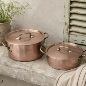 Vintage French copper stew pot set with two lidded copper stock pots and aged brass handles displayed together