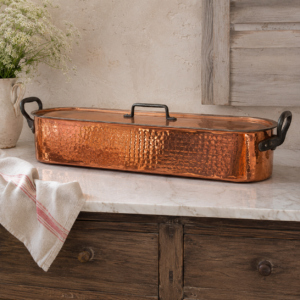 Large vintage French hammered copper fish poacher with lid and removable fish rack displayed in warm copper tones