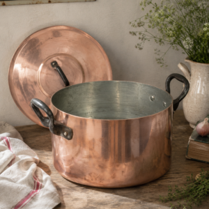 Large vintage French tin-lined copper stockpot with lid and dark metal handles displayed on a white background